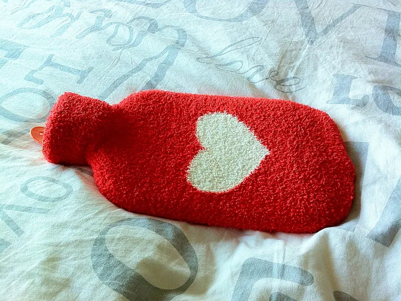 A hot water bottle with a knitted cover